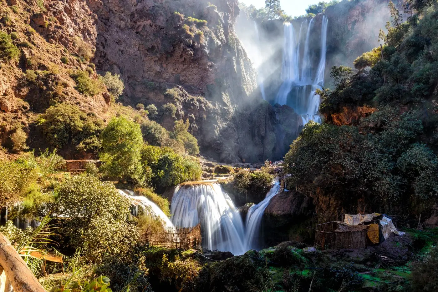 Ouzoud waterfalls cascading down a red rock gorge surrounded by green trees